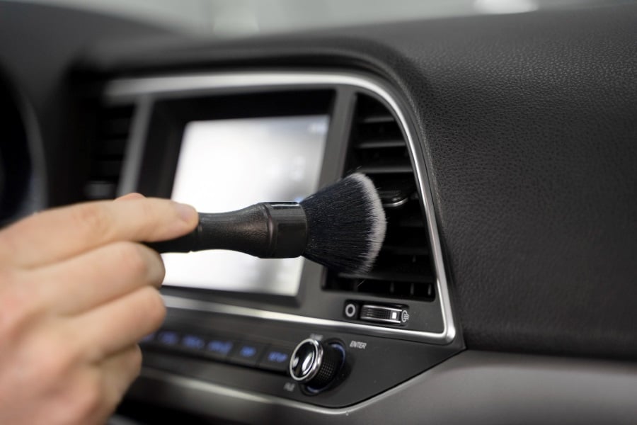 person cleaning car air conditioning grills