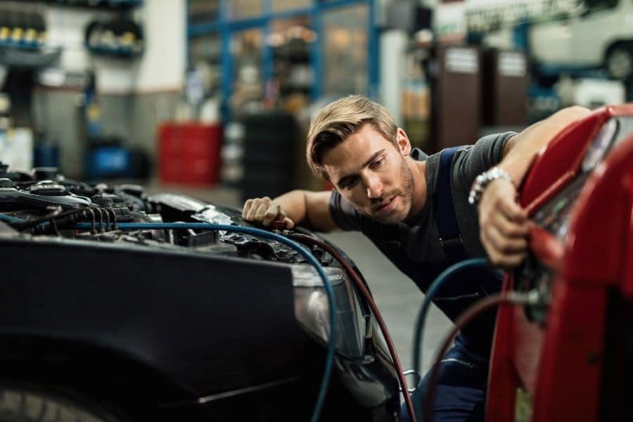 young automobile mechanic using compressor